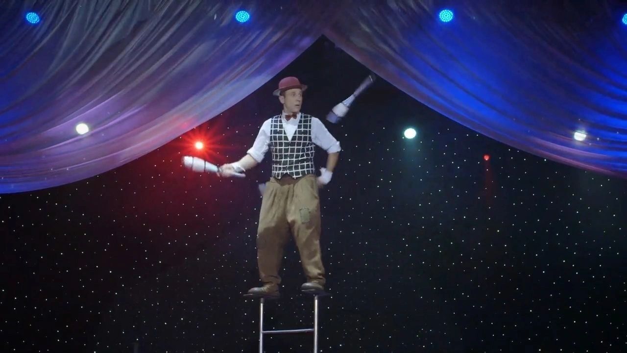 Gregory Popovich juggling clubs on stage under the star curtain